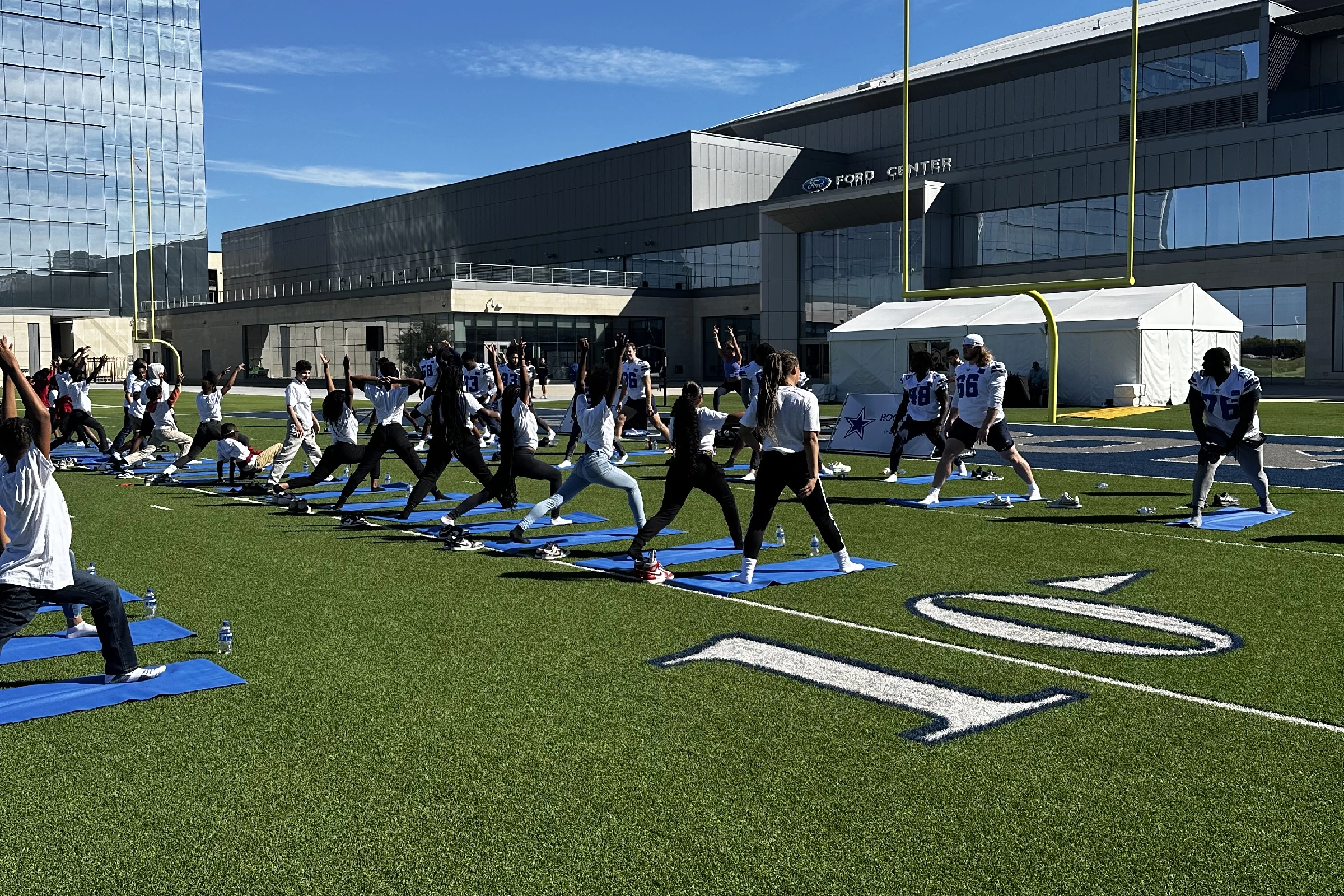Students do yoga on the field with the Dallas Cowboys
