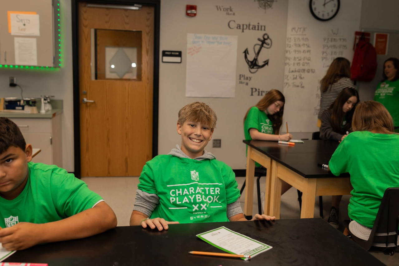 Student smiling wearing green shirt at table