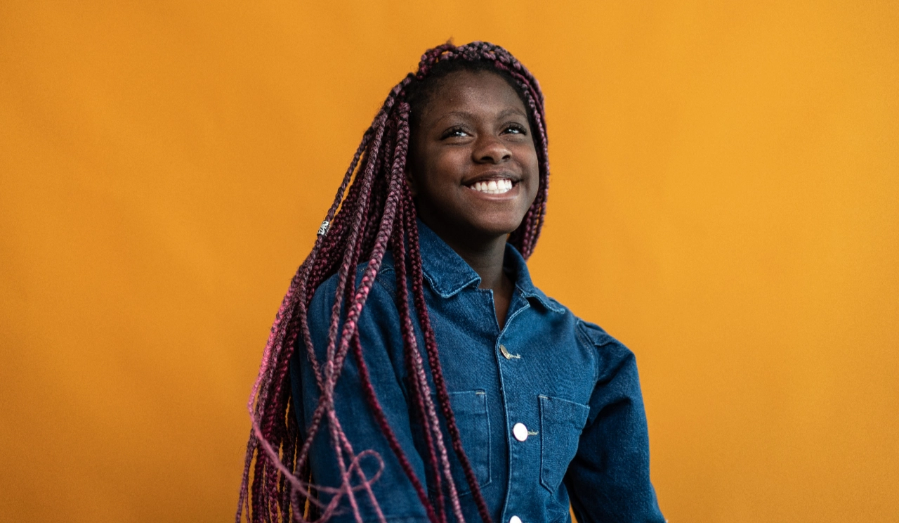 Young woman smiling against orange background
